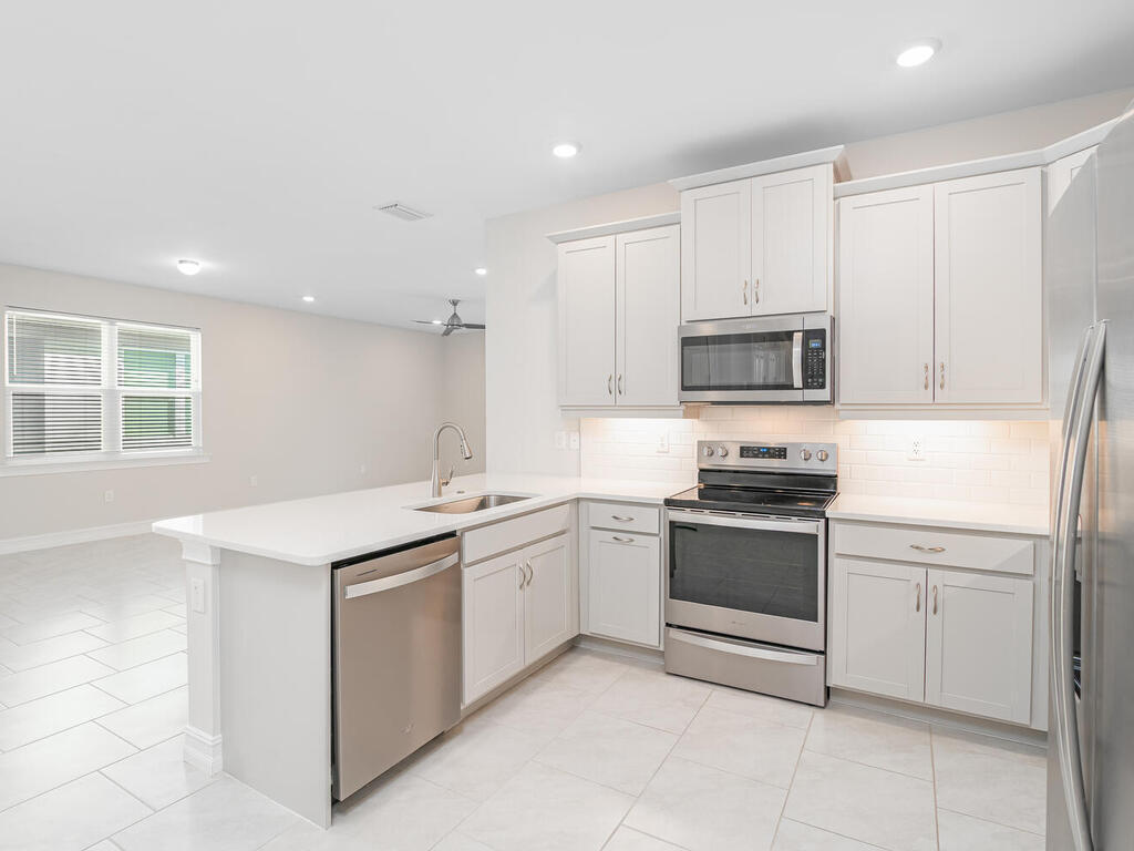 1176 Enbrook Loop Naples, FL 34114 - Photo 5 of 35 a kitchen with stainless steel appliances granite countertop a sink and dishwasher a stove top oven with white cabinets