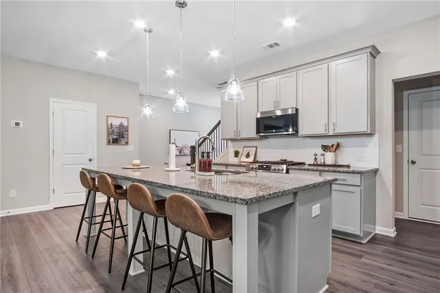 a kitchen with stainless steel appliances granite countertop a table chairs sink and cabinets