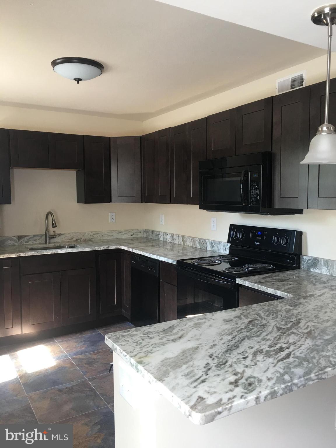 1 Pennsylvania Road, Unit 4 Glassboro, NJ 08028 - Photo 21 of 37 a kitchen with granite countertop a stove a sink and a microwave
