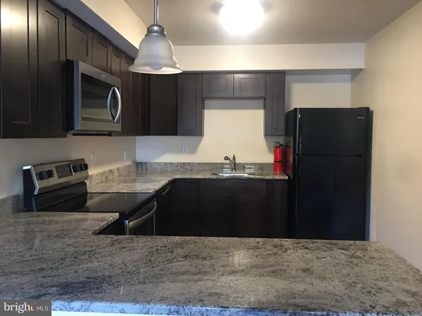 a kitchen with granite countertop a refrigerator and a stove