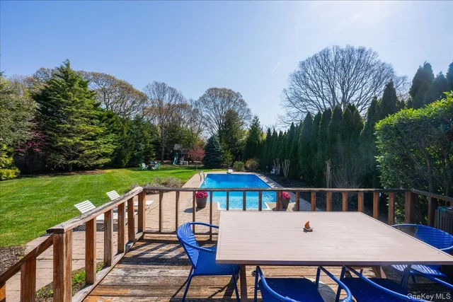 a view of a roof deck with table and chairs under an umbrella with wooden floor and fence