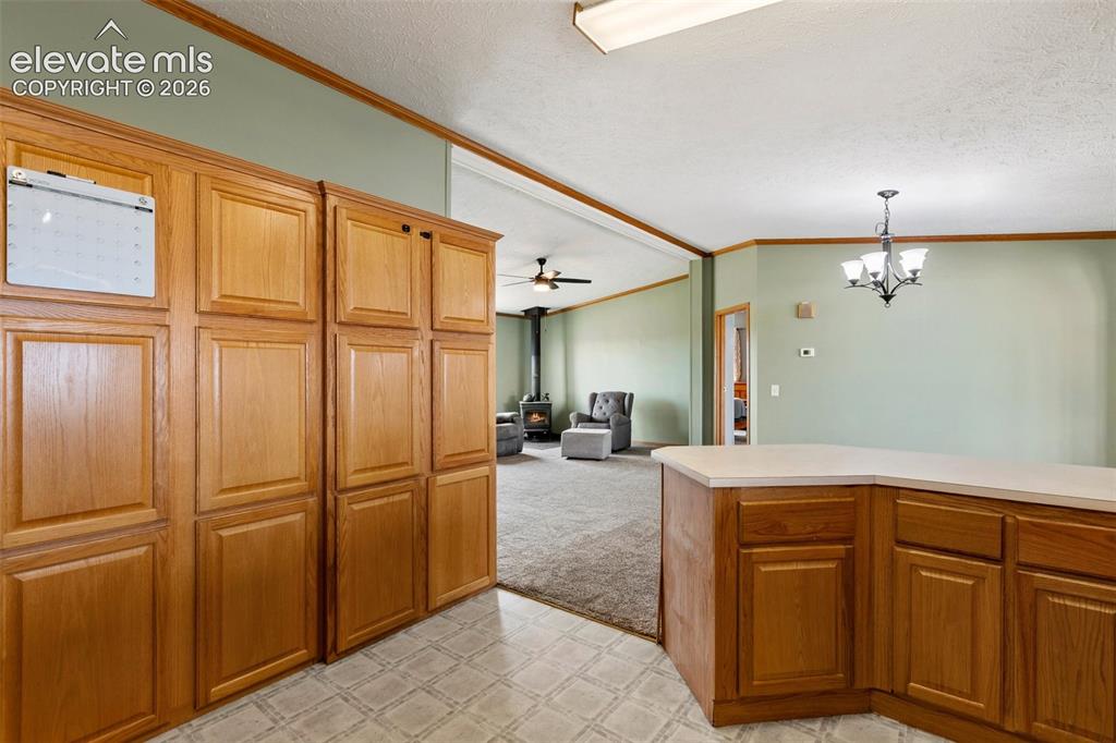 1350 South Calhan Highway Yoder, CO 80864 - Photo 24 of 45 Kitchen featuring extensive wood cabinetry, L-shaped countertop, recessed ceiling light, and patterned floor tiles