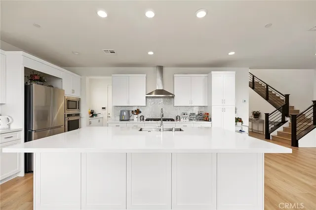 a view of a kitchen with kitchen island a sink a stove a refrigerator cabinets and a living room view
