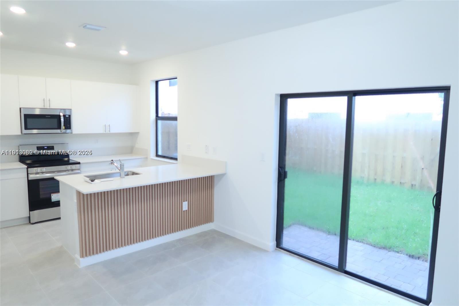 12946 Southwest 231st Street Miami, FL 33170 - Photo 5 of 42 a kitchen with kitchen island a sink a stove and a refrigerator