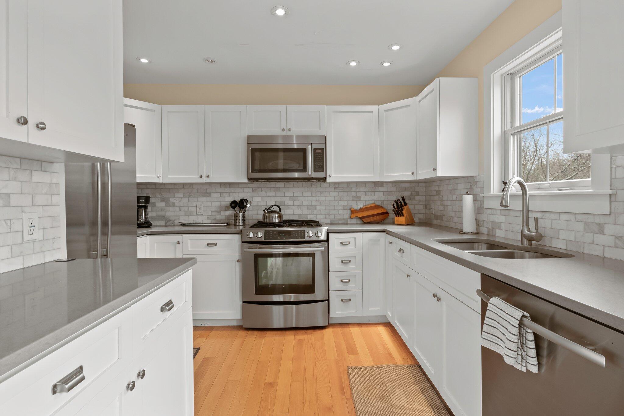 16 Meadow Road, Unit 16 Provincetown, MA 02657 - Photo 5 of 23 a kitchen with stainless steel appliances granite countertop a sink a stove top oven a refrigerator a sink and dishwasher with white cabinets