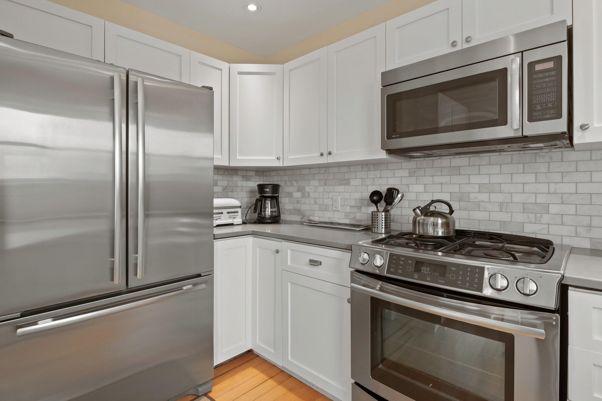 16 Meadow Road, Unit 16 Provincetown, MA 02657 - Photo 6 of 23 a kitchen with stainless steel appliances granite countertop white cabinets a stove top oven