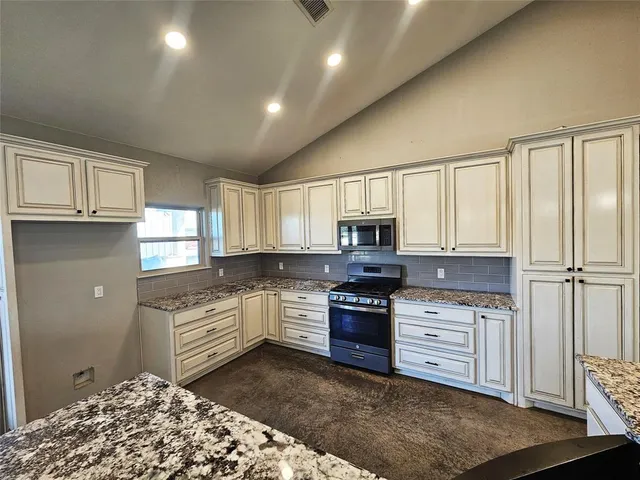 an empty room with ceiling fan and windows