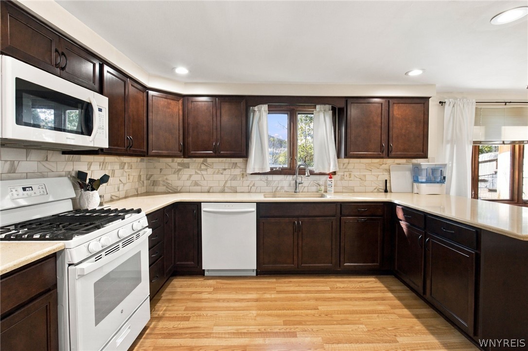 123 Ranch Trail West Amherst, NY 14221 - Photo 8 of 38 Rich dark wood cabinetry pairs beautifully with warm hardwood flooring in this spacious kitchen layout.