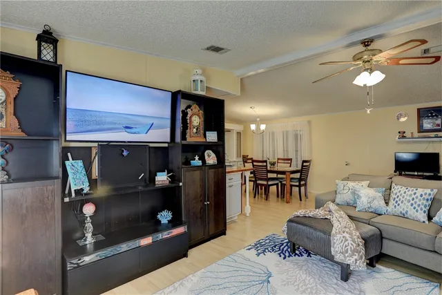 a living room with furniture a flat screen tv and kitchen view