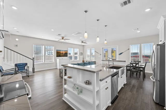 a kitchen with stainless steel appliances granite countertop a dining table chairs refrigerator and sink