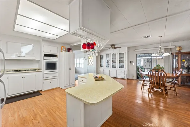 a open kitchen with stainless steel appliances kitchen island granite countertop a table chairs and a refrigerator