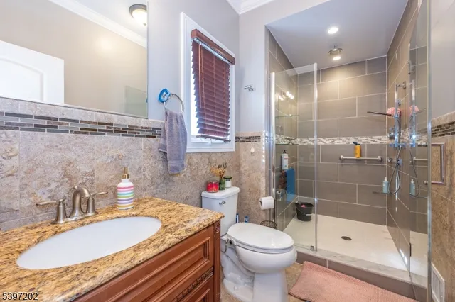 a bathroom with a granite countertop sink a toilet a mirror and shower