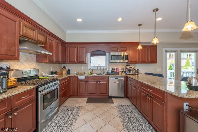 a kitchen with stainless steel appliances granite countertop wooden cabinets a stove top oven a sink and dishwasher