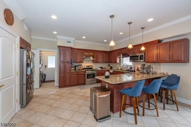 a kitchen with stainless steel appliances kitchen island granite countertop a sink refrigerator and cabinets