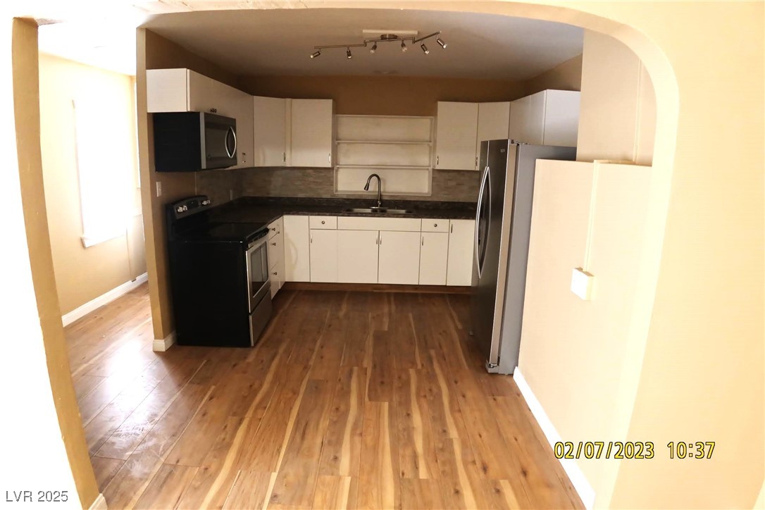 10 East Bonanza Road Las Vegas, NV 89101 - Photo 15 of 35 Kitchen with dark countertops, wood finished floors, stainless steel appliances, and a sink