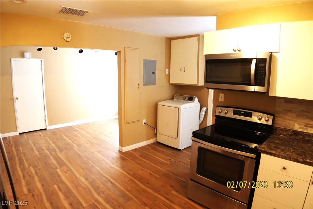 10 East Bonanza Road Las Vegas, NV 89101 - Photo 19 of 35 Kitchen with white cabinets, stainless steel appliances, wood finished floors, washer / dryer, and electric panel