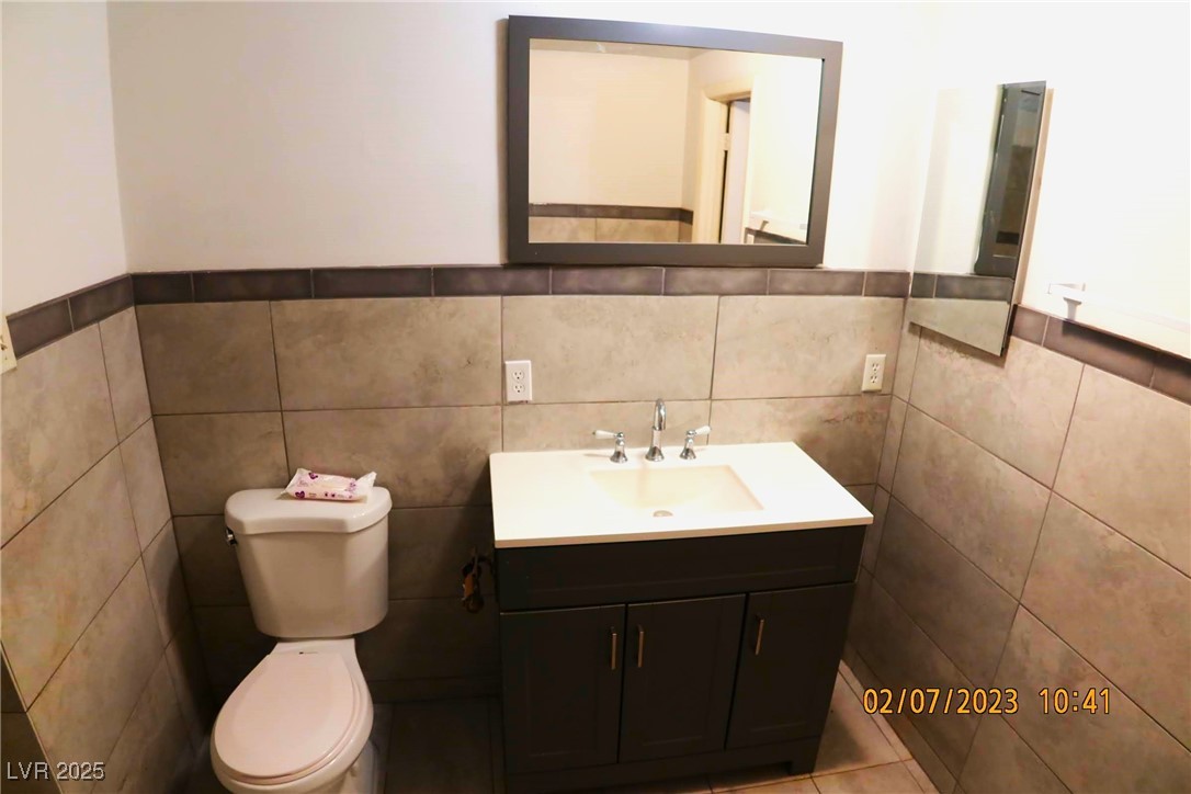 10 East Bonanza Road Las Vegas, NV 89101 - Photo 27 of 35 Bathroom featuring tile walls, toilet, vanity, and wainscoting