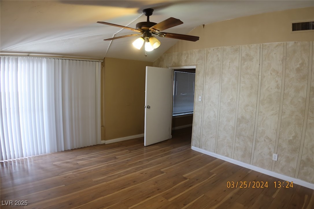 10 East Bonanza Road Las Vegas, NV 89101 - Photo 3 of 35 Empty room featuring a ceiling fan, baseboards, wood-type flooring, lofted ceiling, and visible vents