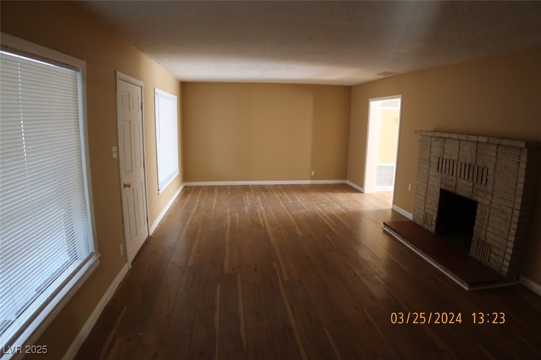 10 East Bonanza Road Las Vegas, NV 89101 - Photo 6 of 35 Unfurnished living room featuring hardwood / wood-style flooring, baseboards, and a fireplace