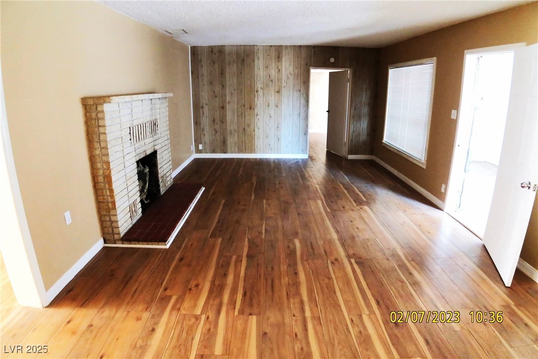 10 East Bonanza Road Las Vegas, NV 89101 - Photo 9 of 35 Unfurnished living room featuring baseboards, hardwood / wood-style floors, wooden walls, and a fireplace