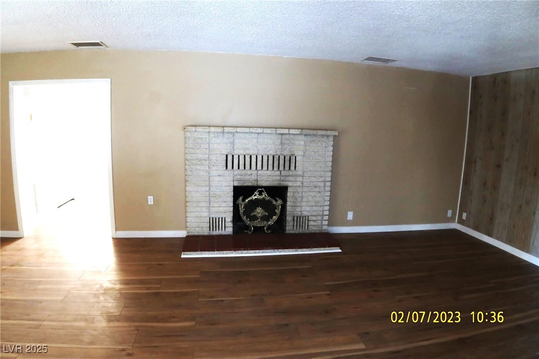 10 East Bonanza Road Las Vegas, NV 89101 - Photo 10 of 35 Unfurnished living room with a brick fireplace, wood finished floors, visible vents, and baseboards