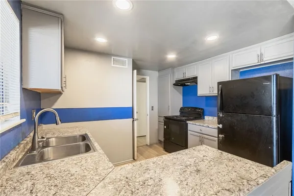 a kitchen with stainless steel appliances kitchen island granite countertop a refrigerator and a sink