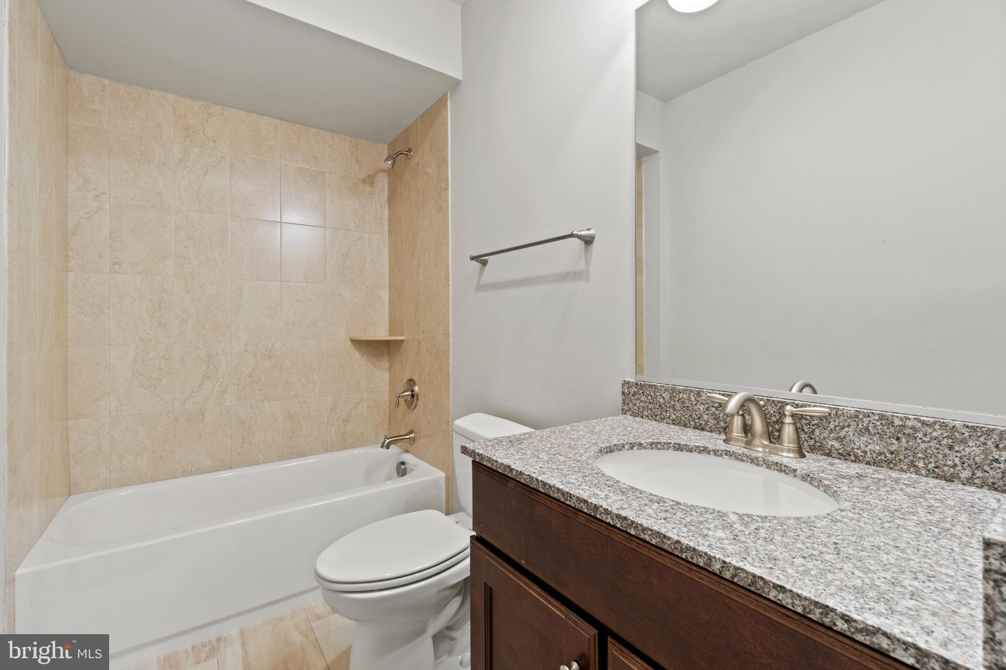 13725 Orlando Road Nokesville, VA 20181 - Photo 62 of 65 a bathroom with a granite countertop sink a toilet a mirror a bathtub and shower