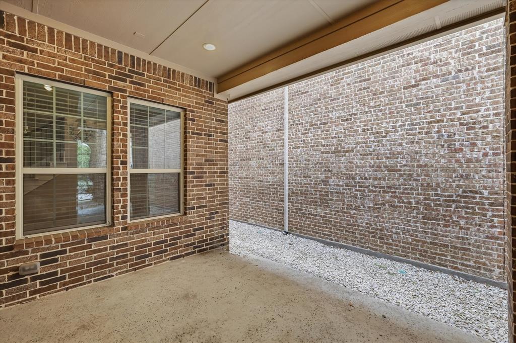 768 Huntingdon Street Coppell, TX 75019 - Photo 30 of 37 Quiet side-yard patio space with brick privacy walls, covered shade, and easy-care rock landscaping for simple lock-and-leave living.