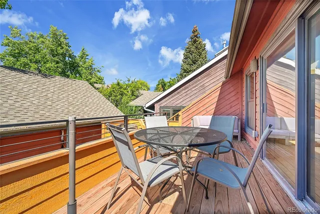 a view of a patio with table and chairs with wooden floor and fence