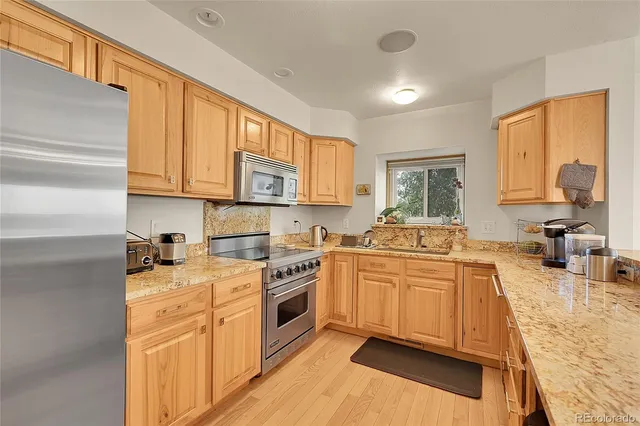 a kitchen with stainless steel appliances granite countertop a stove a sink and a refrigerator