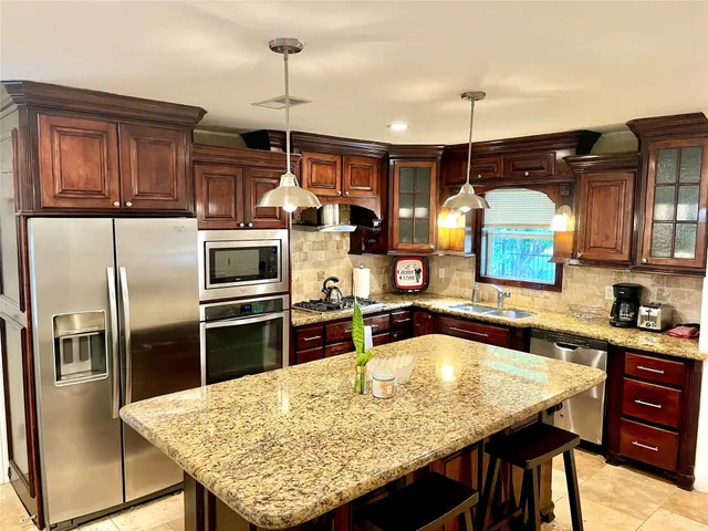 a kitchen with stainless steel appliances granite countertop a sink a stove and refrigerator