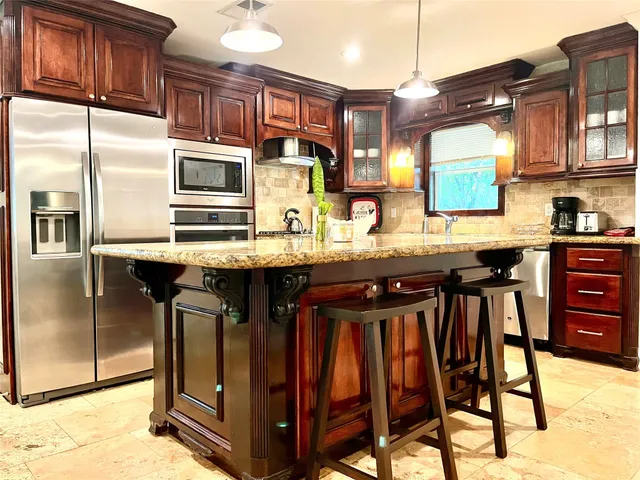 a kitchen with stainless steel appliances kitchen island granite countertop a table chairs in it and a window