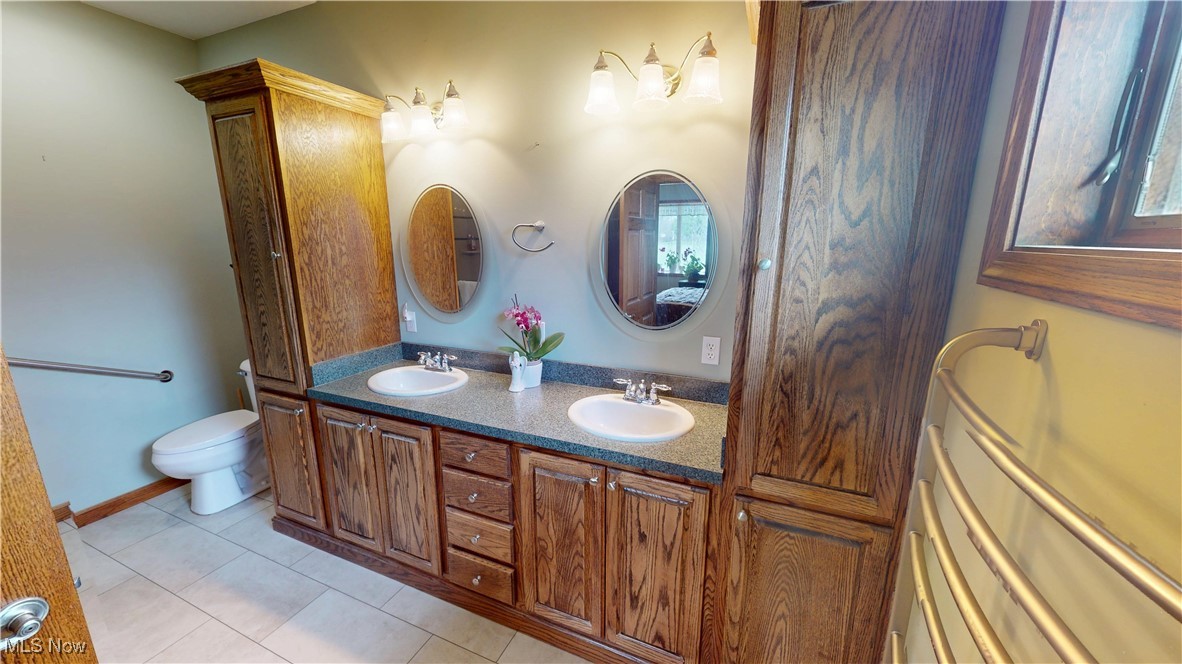 10323 Smith Road Litchfield, OH 44253 - Photo 23 of 50 Bathroom with double vanity, a sink, toilet, and tile patterned floors
