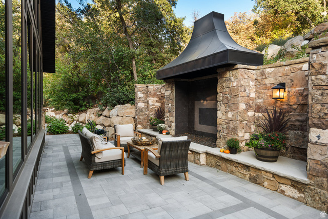 1141 South Oak Leaf Lane Springville, UT 84663 - Photo 122 of 147 Expansive outdoor patio featuring paver flooring, a built-in stone fireplace with a metal hood, and a stone retaining wall