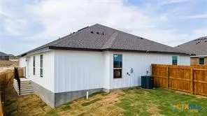 a view of a house with backyard and wooden fence