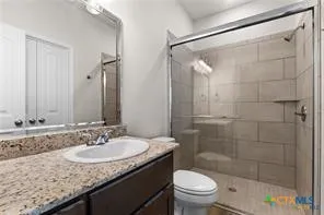 a bathroom with a granite countertop sink a toilet and shower