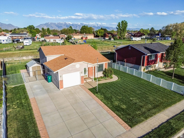 5896 South 3950th Street West Roy, UT 84067 - Photo 28 of 29 View of front facade featuring driveway, an attached garage, a residential view, and a mountain view