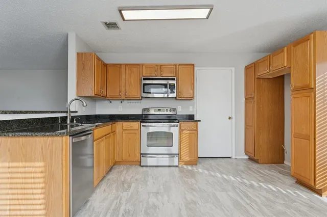 a kitchen with granite countertop a stove top oven sink and cabinets