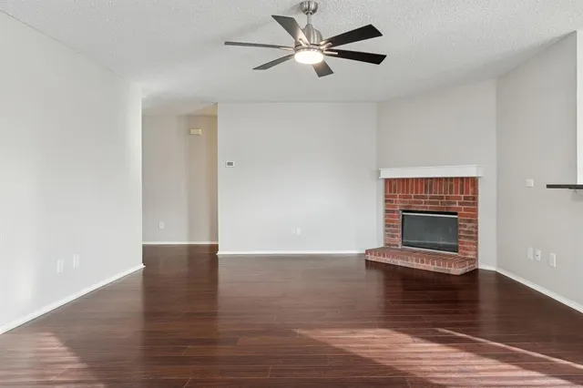 a view of an empty room with wooden floor ceiling fan
