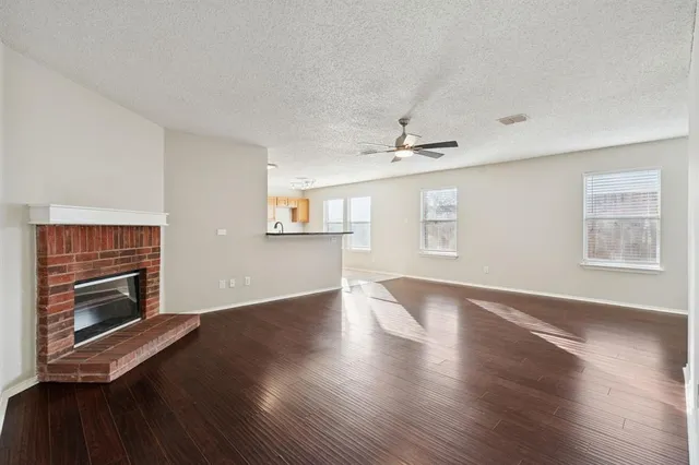 a view of an empty room with wooden floor fireplace and a window