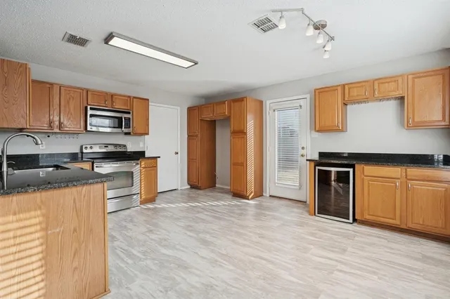 a kitchen with granite countertop a stove top oven a sink dishwasher and a refrigerator with wooden floor