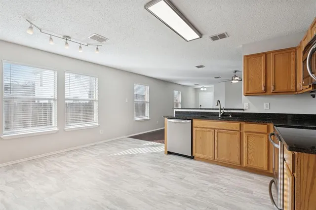 a kitchen with granite countertop a stove a sink and a refrigerator