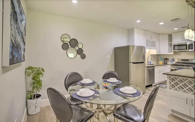 a kitchen with stainless steel appliances granite countertop a dining table and chairs with wooden floor