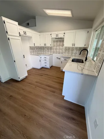 a kitchen with stainless steel appliances granite countertop a sink dishwasher stove top oven and cabinets with wooden floor