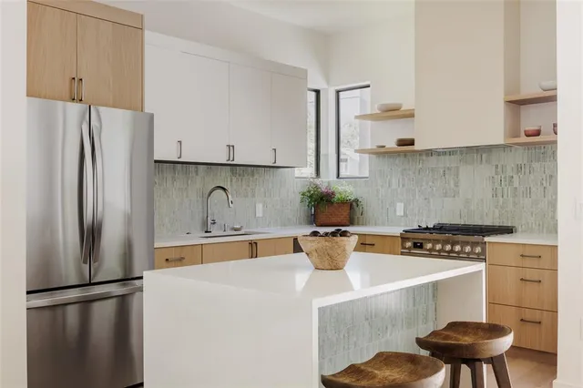 a kitchen with stainless steel appliances a refrigerator a stove a sink and white cabinets