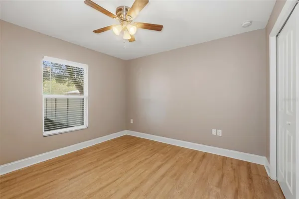 a view of empty room with wooden floor and fan