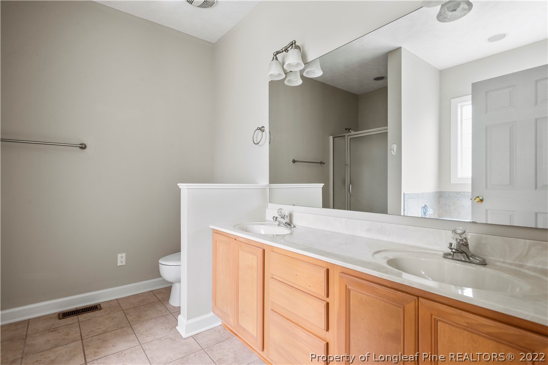 3612 Talus Road Fayetteville, NC 28306 - Photo 21 of 29 a bathroom with a granite countertop sink a toilet and a mirror