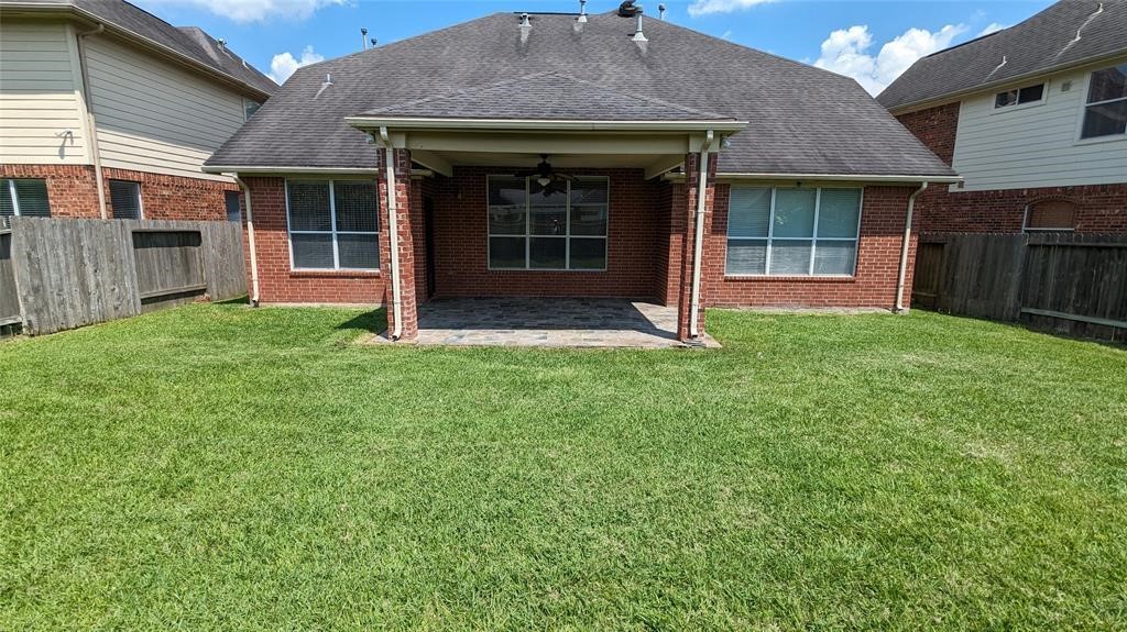 20909 Springport Court Katy, TX 77450 - Photo 34 of 39 Spacious backyard with a charming brick exterior and a covered patio, perfect for outdoor gatherings and relaxation.