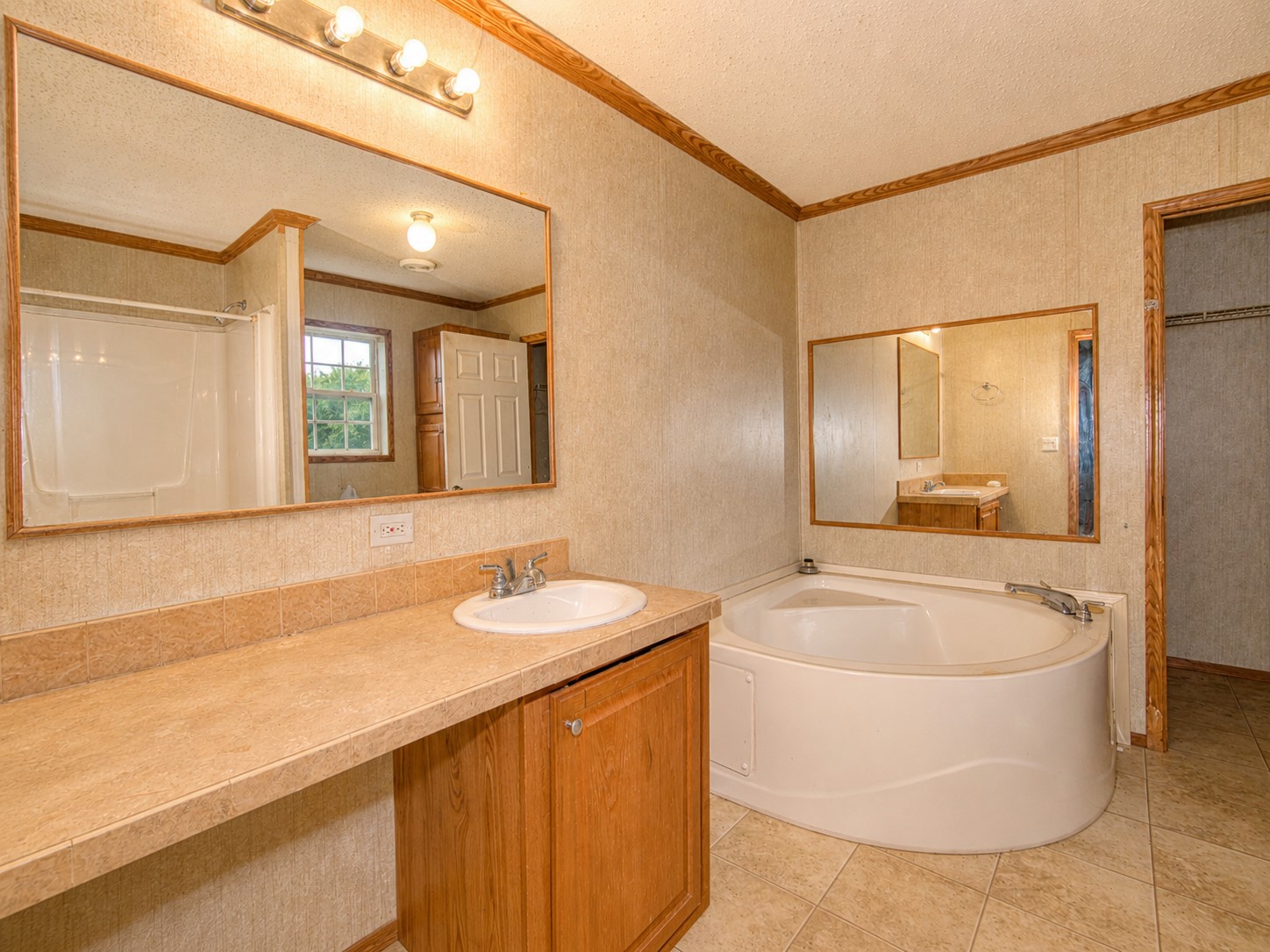 461924 East 1140 Road Sallisaw, OK 74955 - Photo 17 of 29 Built-in corner soaking tub, vanity with integrated sink, and wood-finish cabinetry