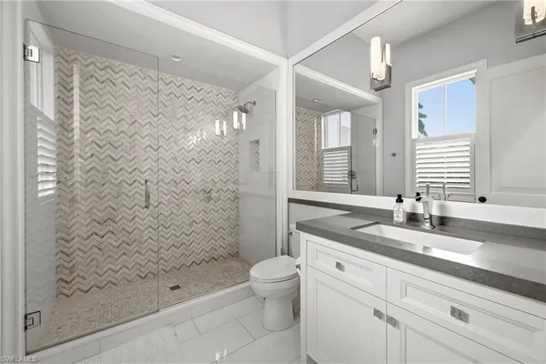 a bathroom with a granite countertop sink a toilet and shower